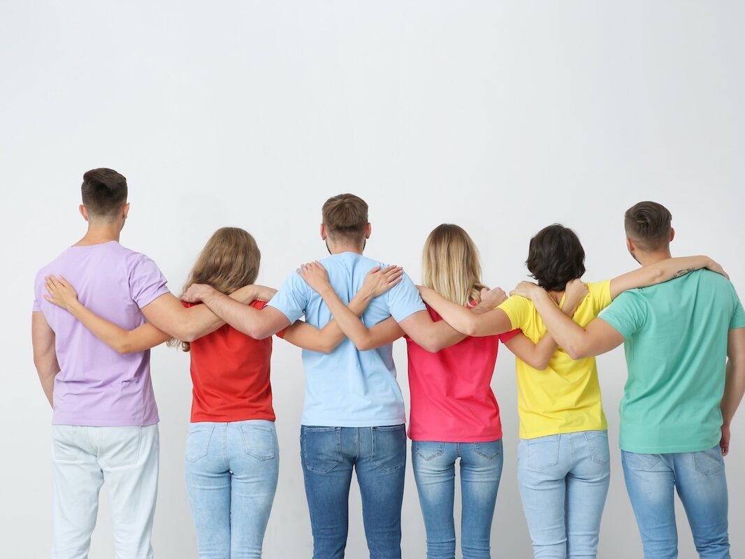 Group of young people hugging each other on light background. Unity concept