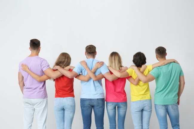 Group of young people hugging each other on light background. Unity concept